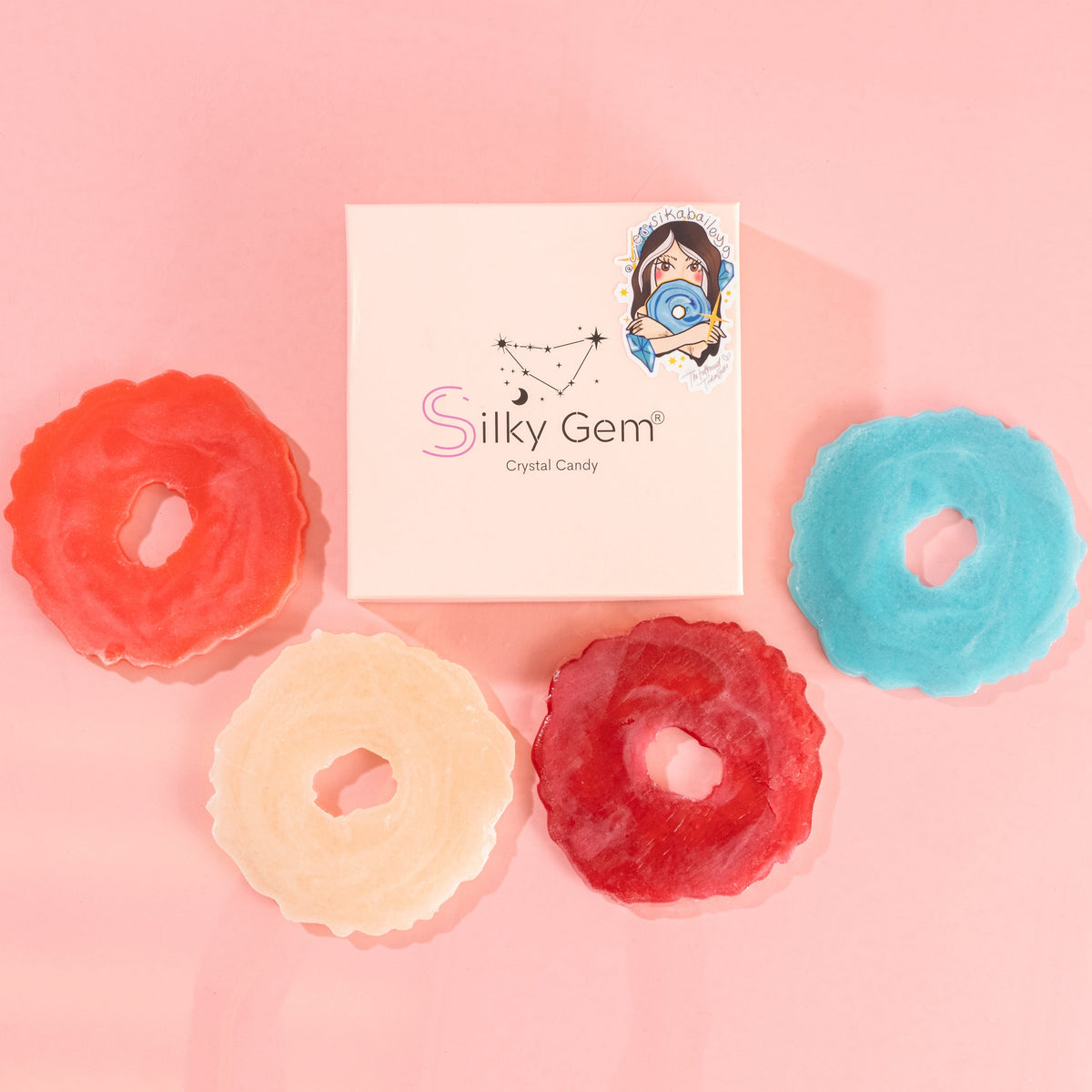 Colorful Silky Gem crystal candy in pink, blue, and red alongside a gift box
