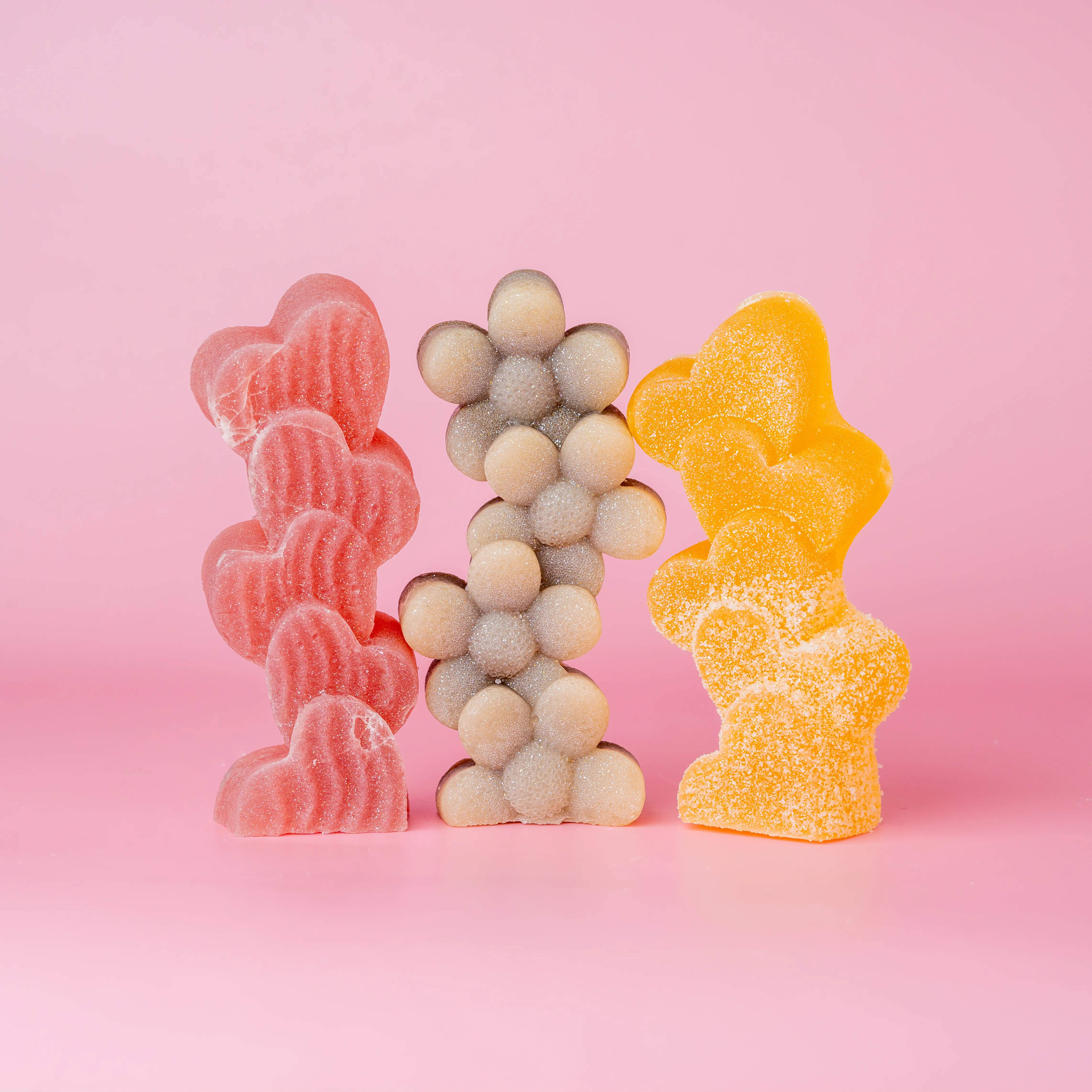 Trio of candies half dusted with sugar. Shaped as heart with red color, part white and brown flower shaped, yellow hearts.