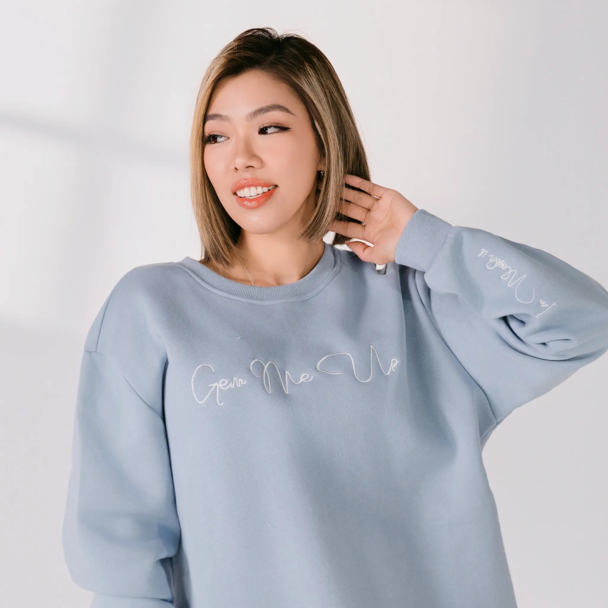 Woman wearing a light blue sweatshirt with text on it against a white background