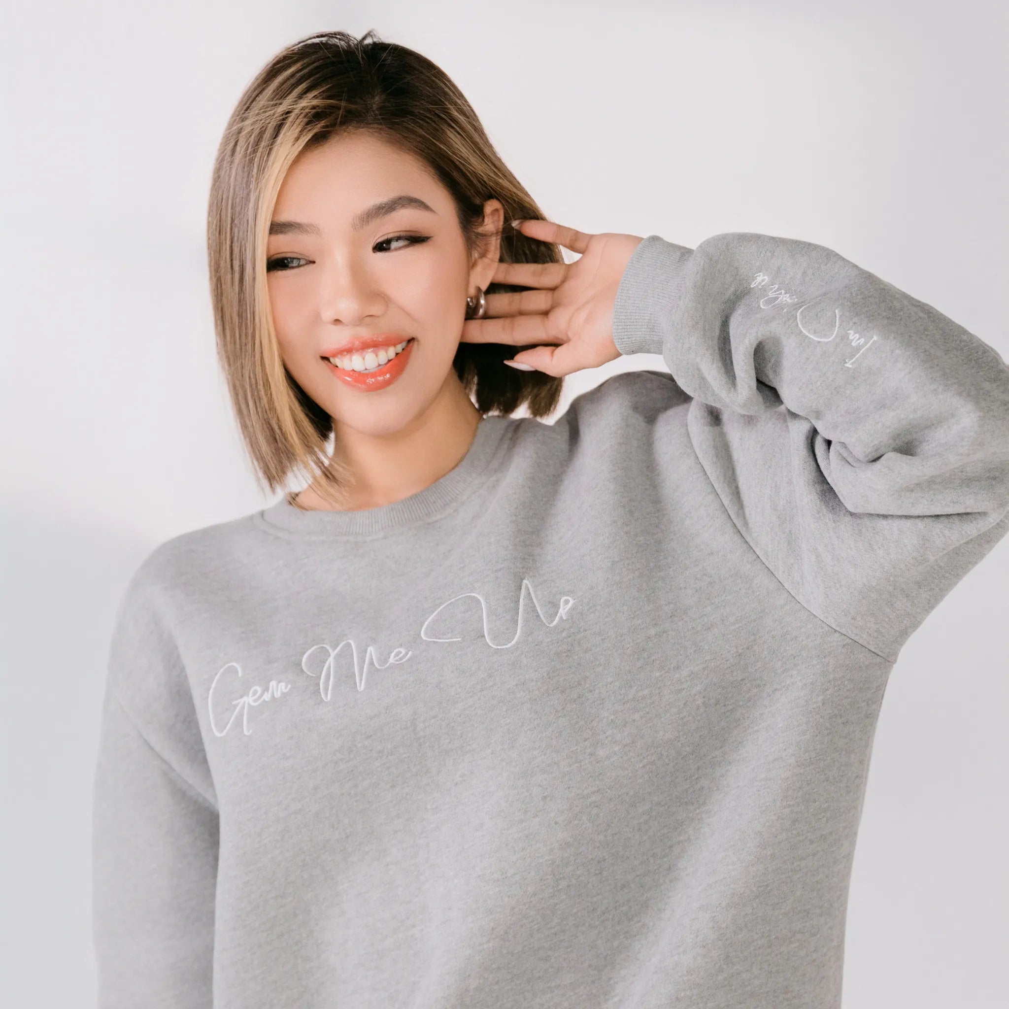 Woman wearing a gray sweatshirt with text on a plain background
