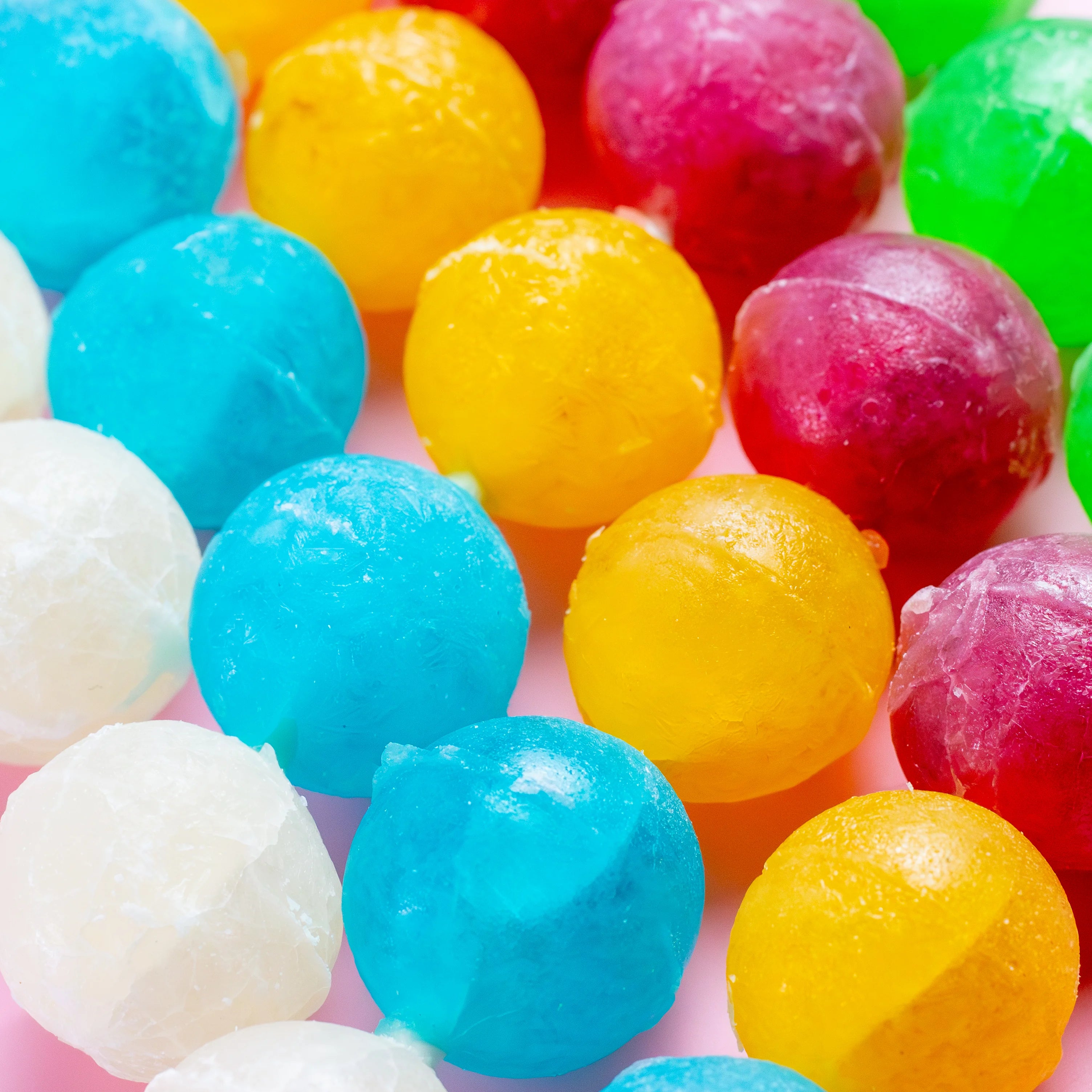 Close-up of colorful gumballs on a pink background