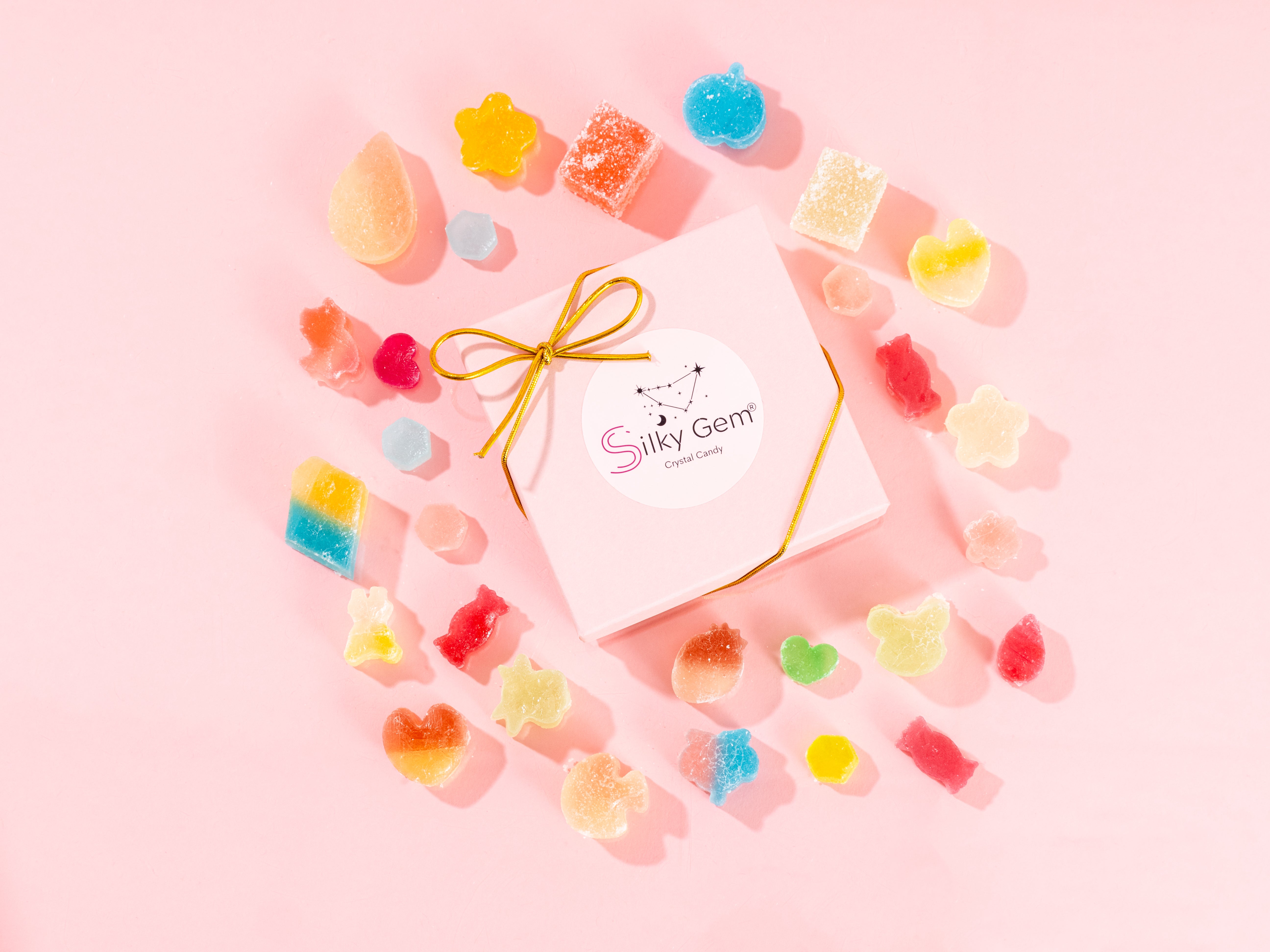Silky Gem product packaging surrounded by colorful gummy bears on a pink background