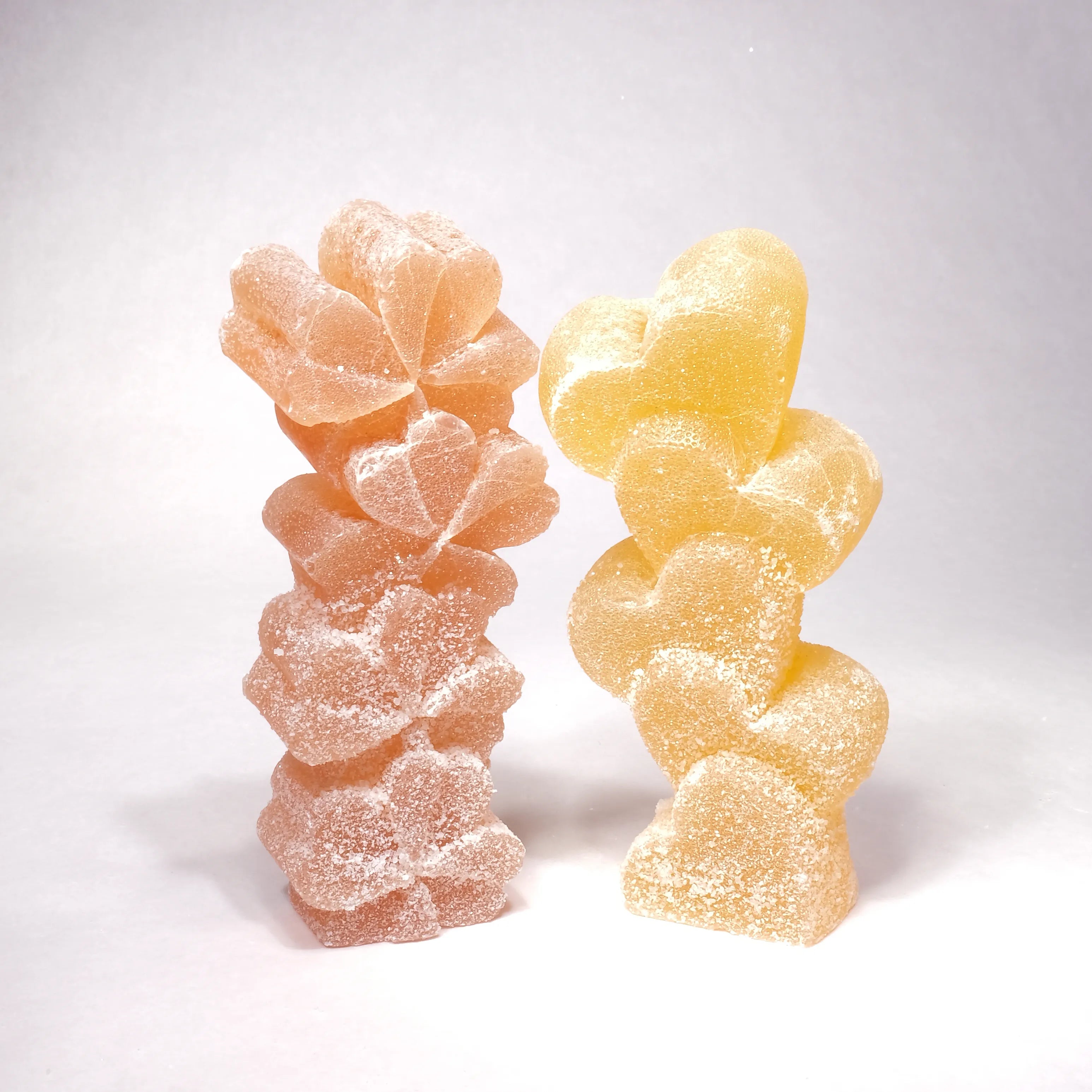 Two gummy candy worms, one pink and one yellow, on a white background