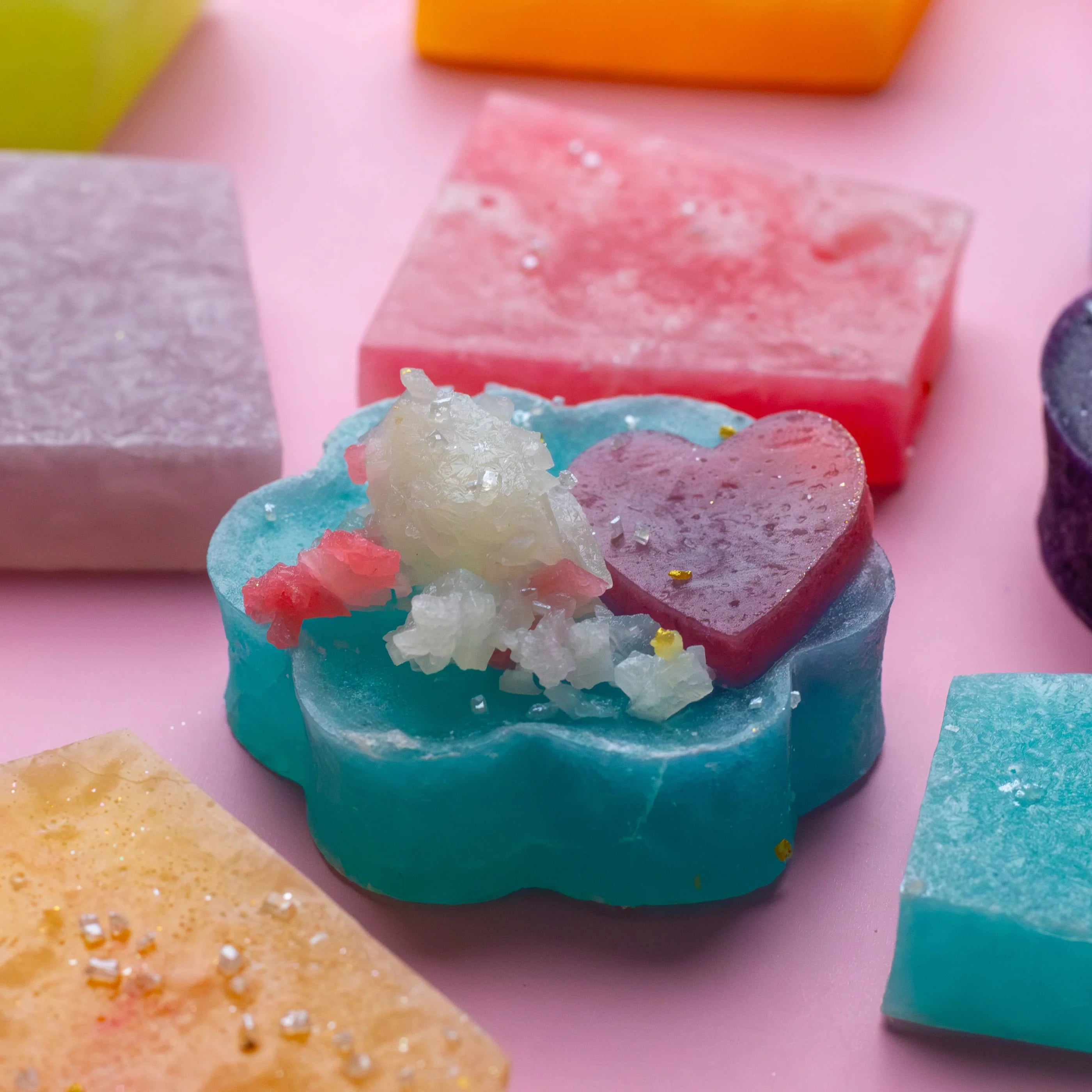 Colorful soap bars with decorative elements on a pink background