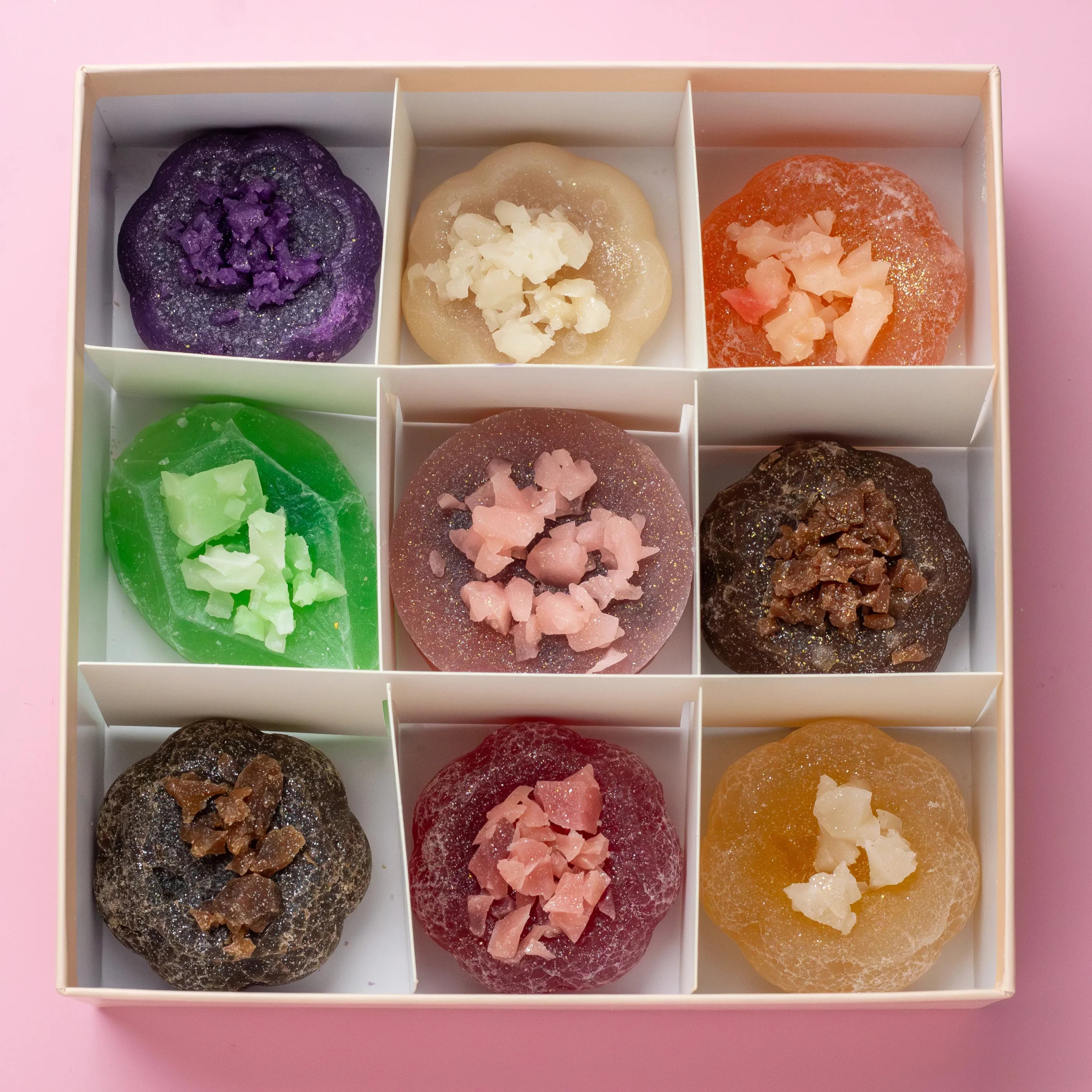 Assorted colorful gummy candies in a box on a pink background