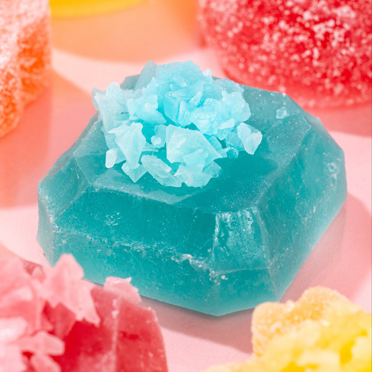 Close-up of vibrant blue Silky Gem crystal candy piece from The Golden Lava collection on a pink background.