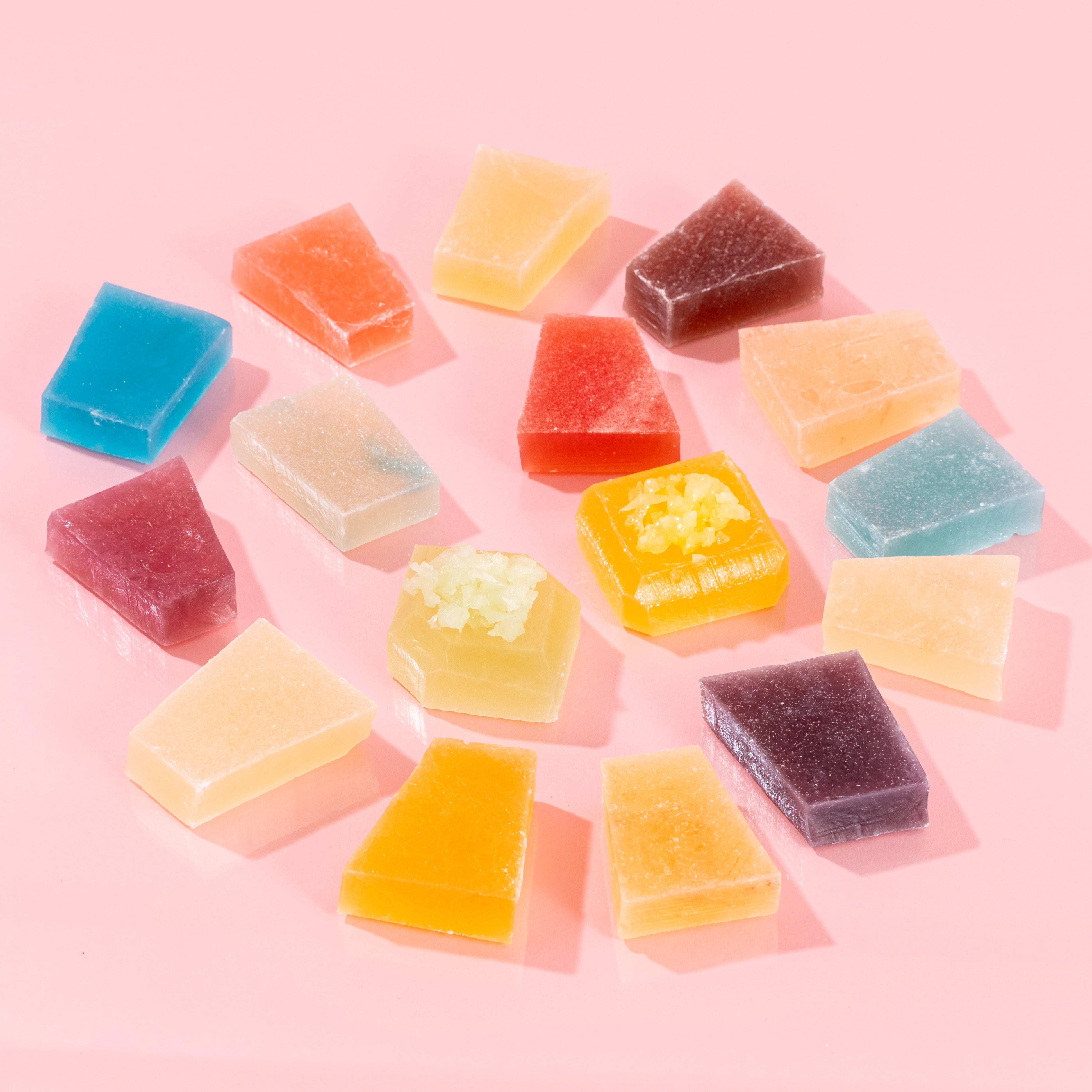 Handcrafted Silky Gem® crystal candies from the Treasure Box collection, featuring signature geometric gem cuts with a firm, jewel-toned appearance, arranged in a circular pattern on a light pink background.