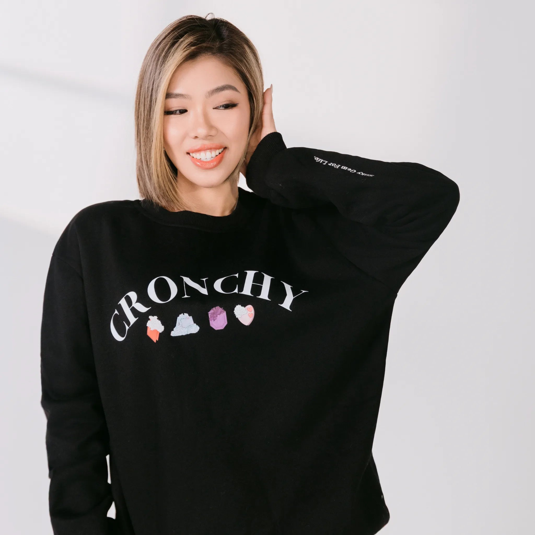 Person wearing a black sweatshirt with 'CRUNCHY' and colorful graphics on a white background