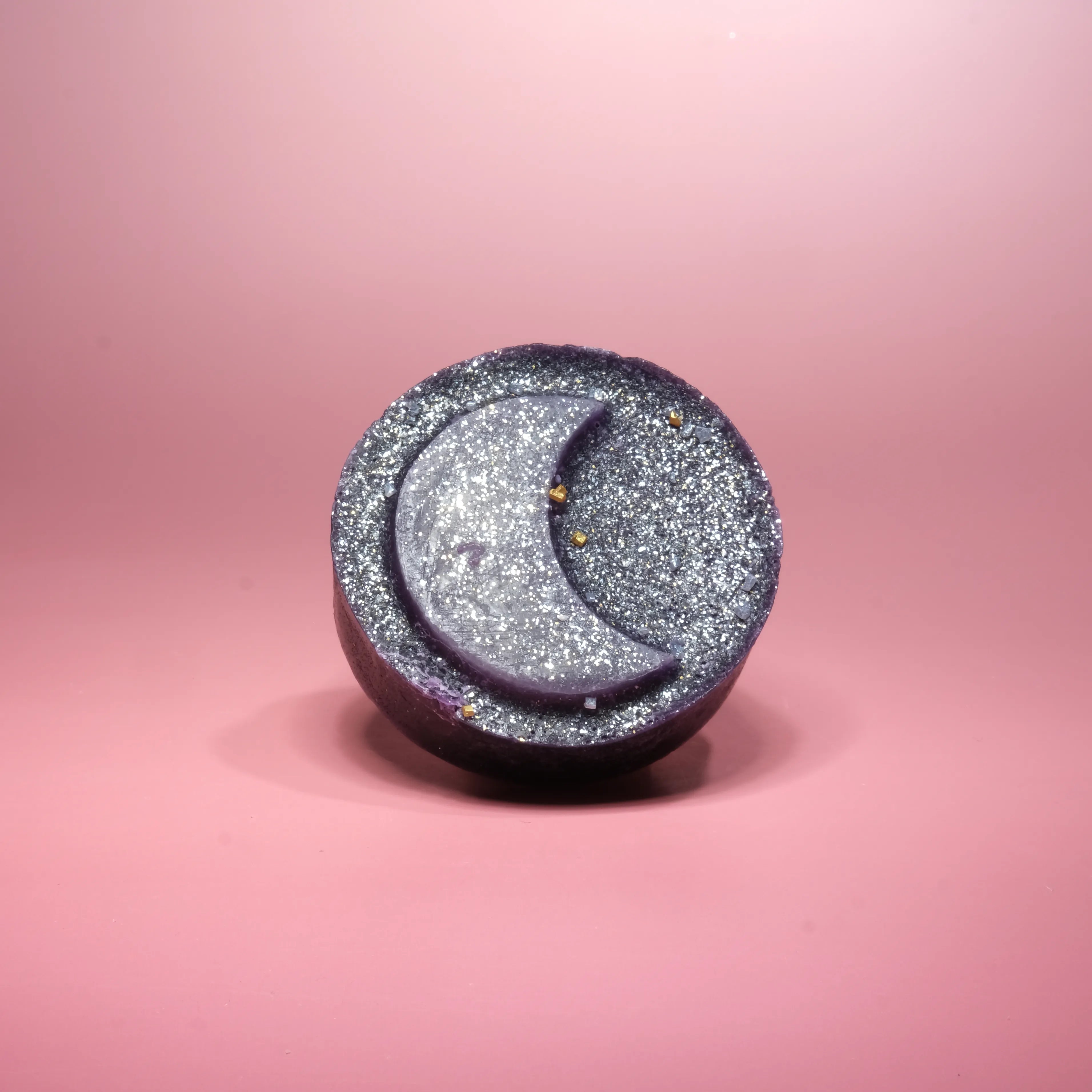 Handcrafted ube coconut crystal candy with a sparkling purple shell and soft jelly center, topped with coconut crystal pieces on a pink background.