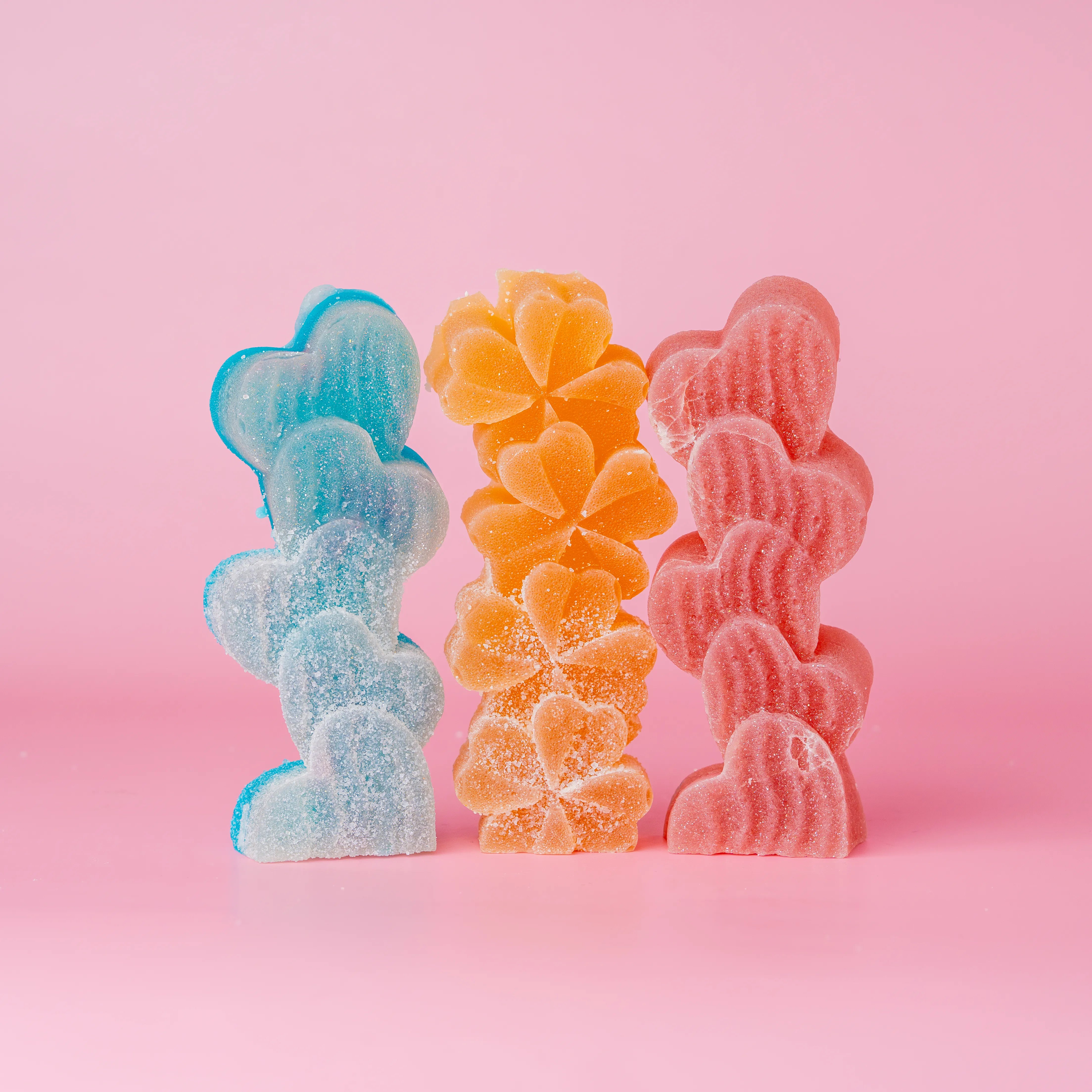 Trio of candies dusted with sour sugar. Bluea heart shape, orange flowers, and red hearts.