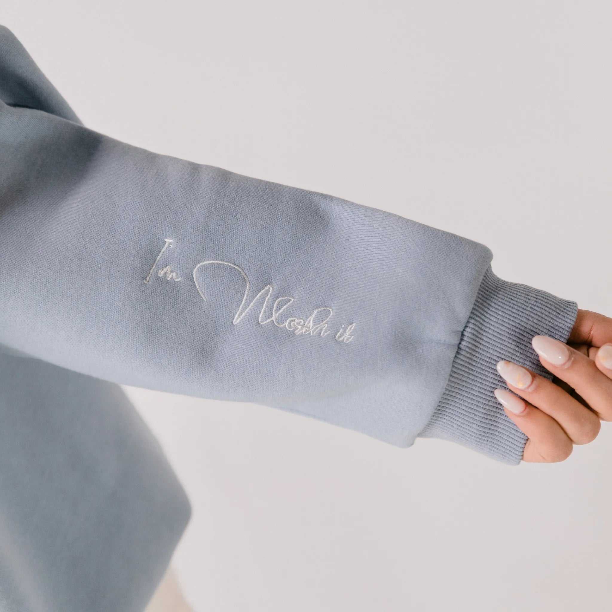 Gray sweatshirt sleeve with 'I'm Worth It' text on a light gray background