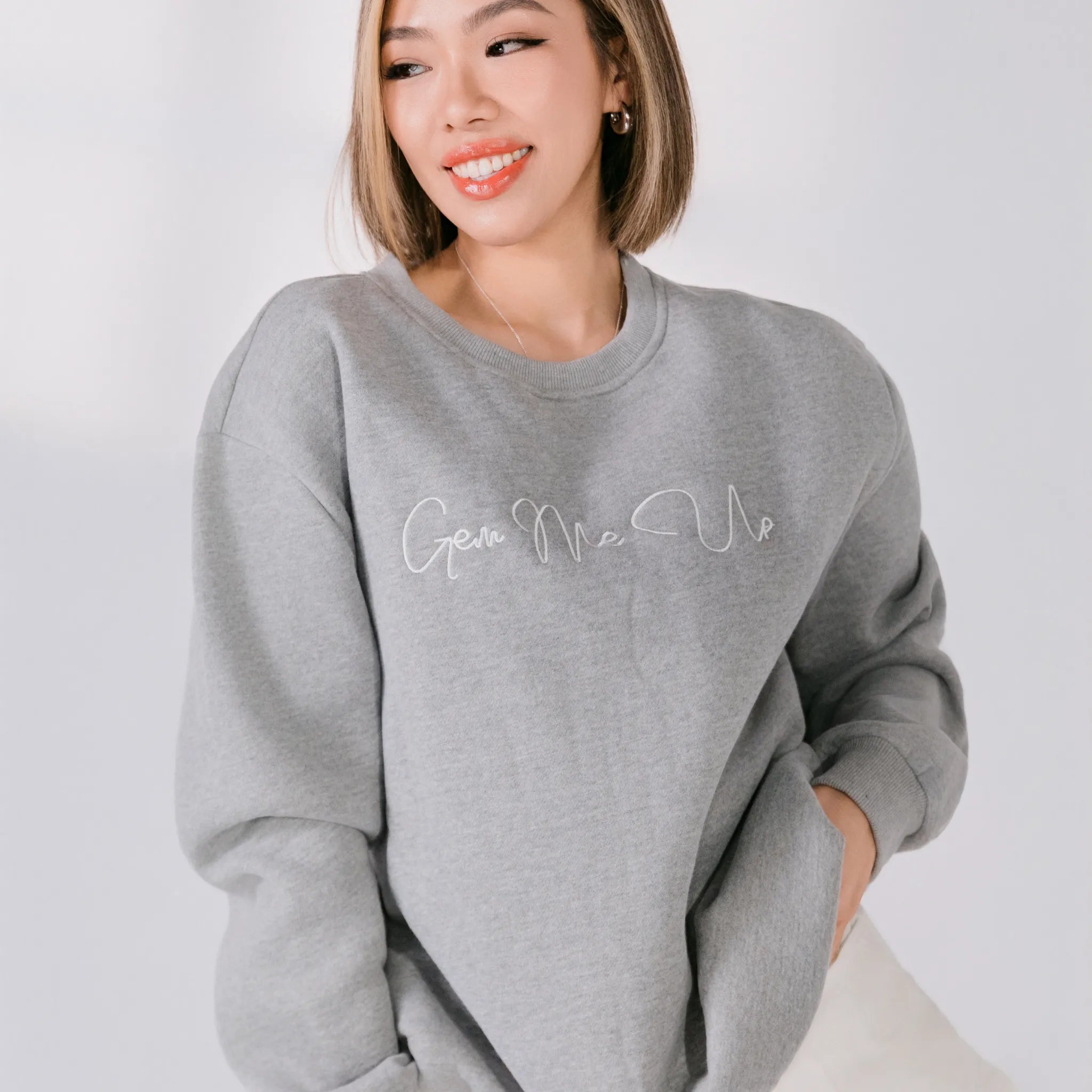 Person wearing a gray sweatshirt with 'Give Me Me' text on a white background