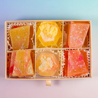 A box of assorted Silky Gem® Peach Moonstone candies with a mix of orange and peach colors and sparkling inclusions, presented in a partitioned cardboard box.