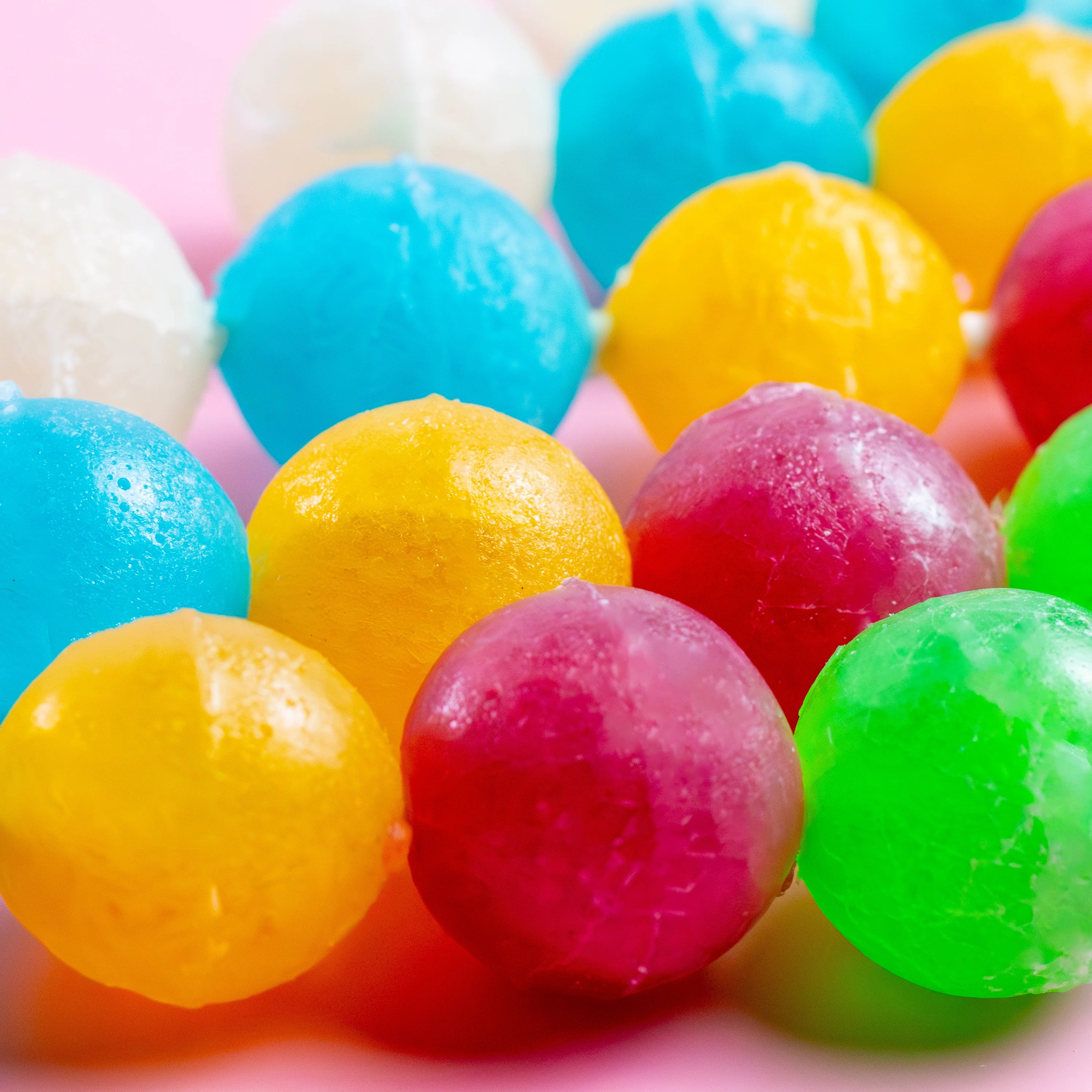 Close-up of colorful gumballs on a pink background