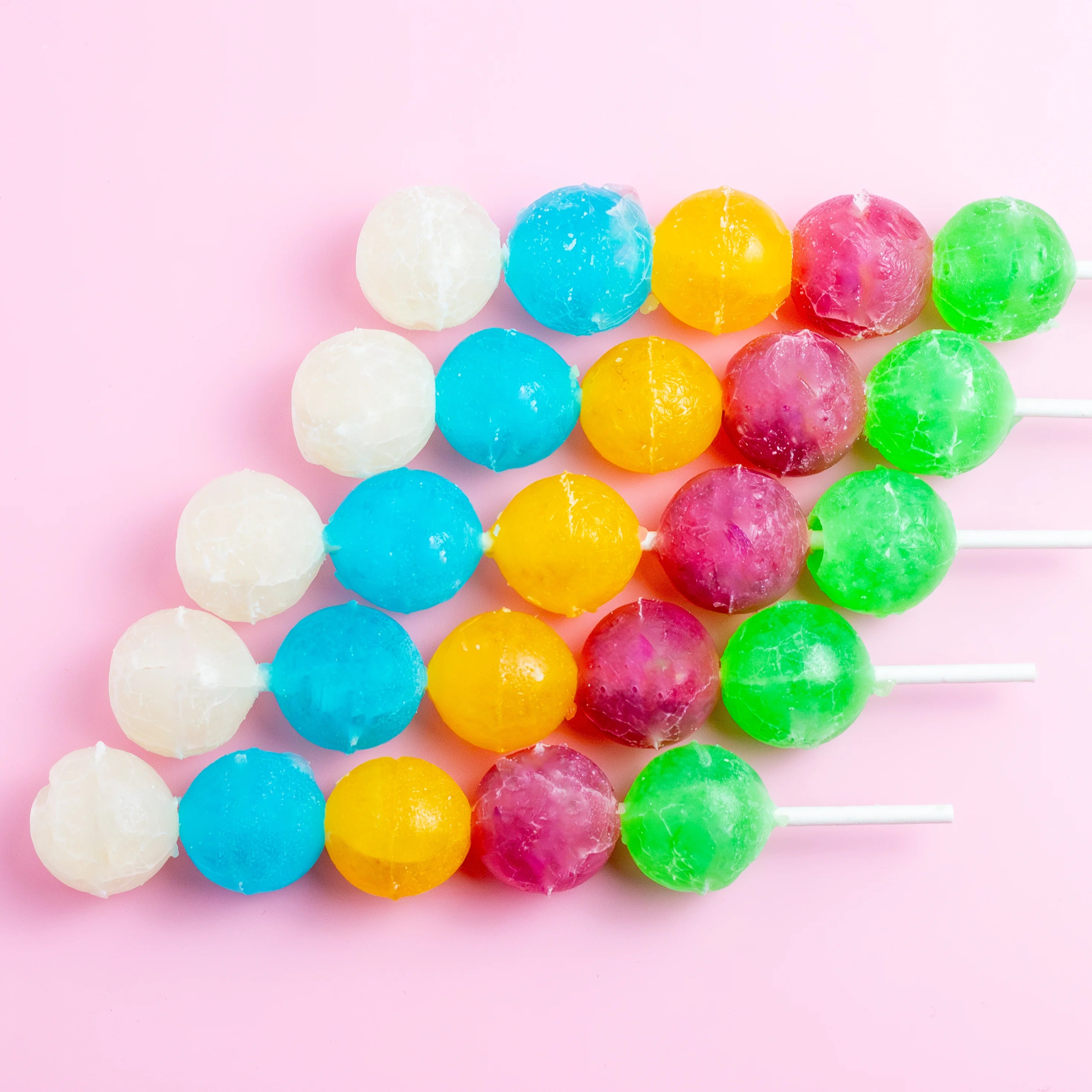 Colorful gumball lollipops on a pink background