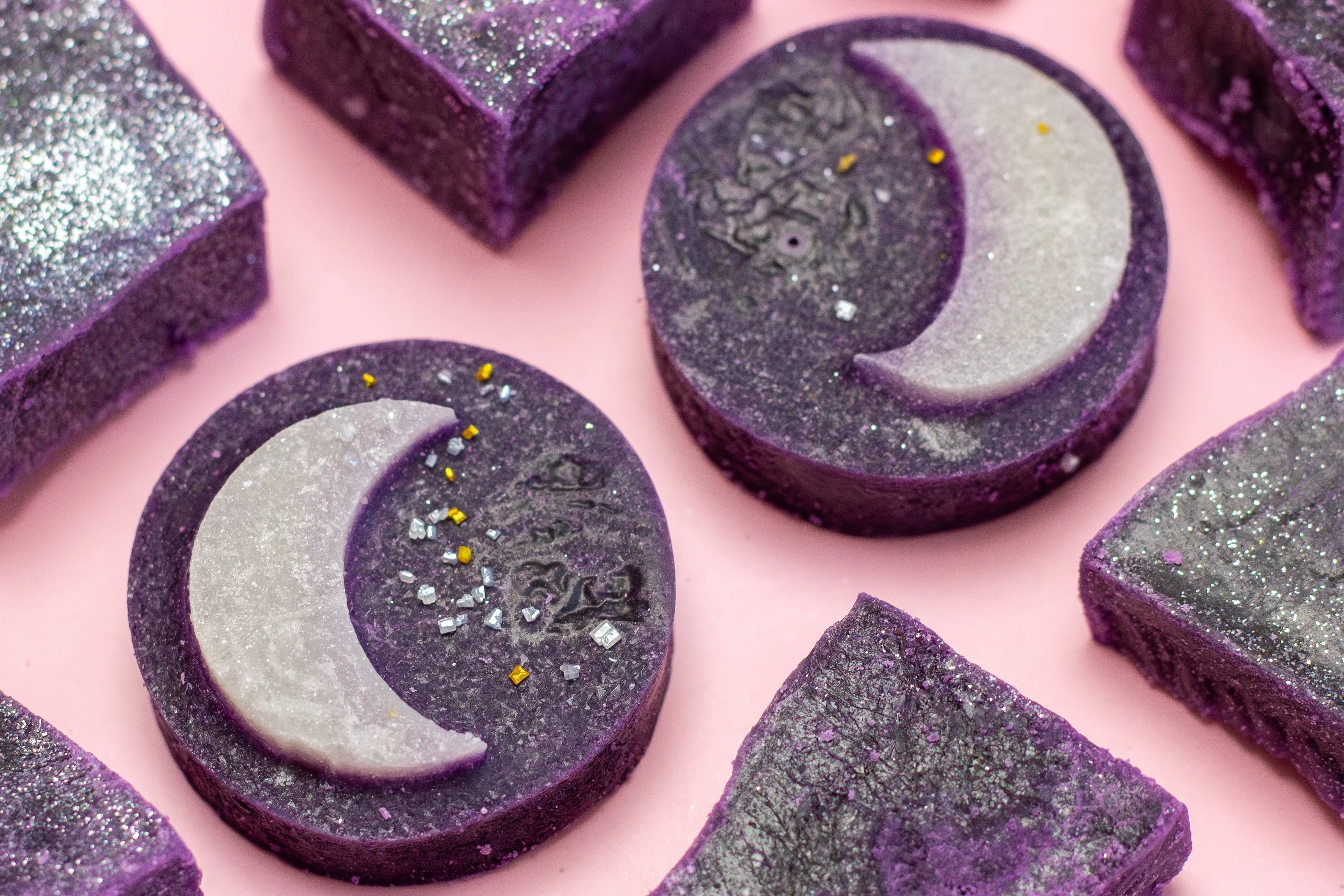 Purple soap bars with moon designs on a pink background
