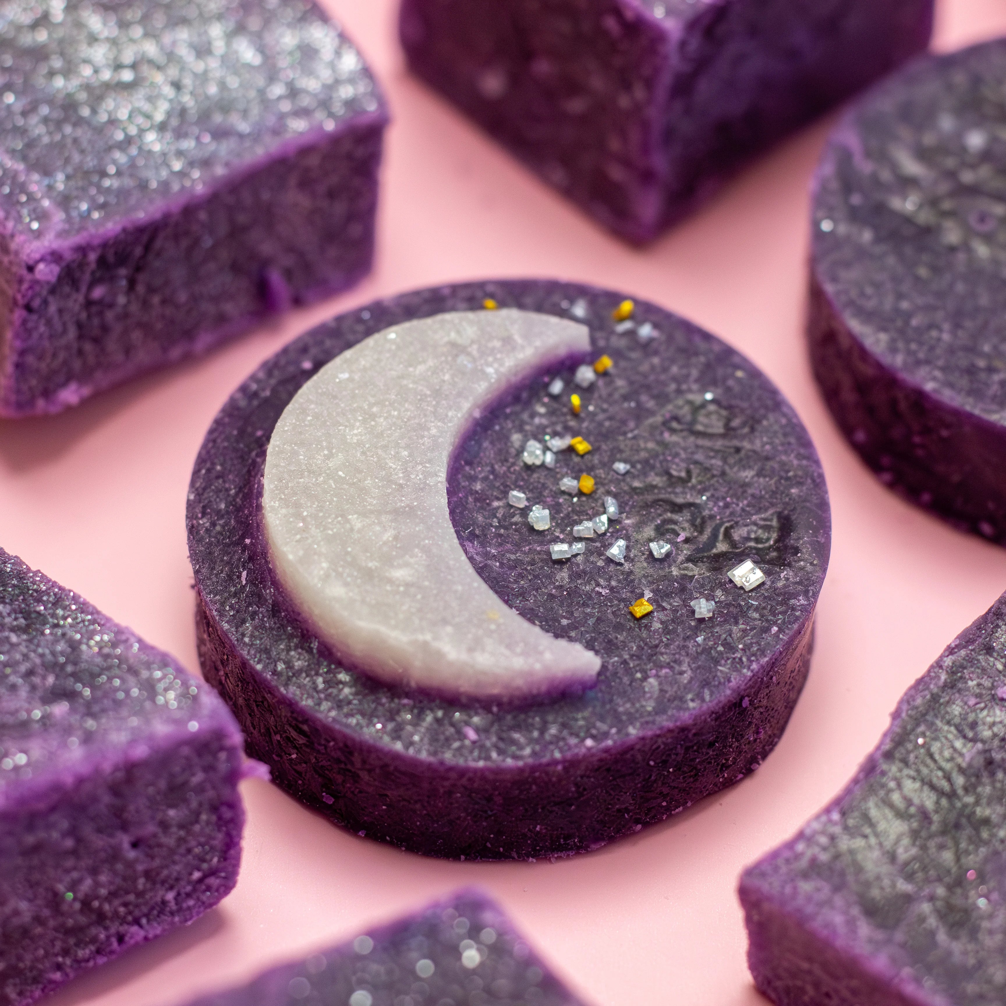 Purple soap bars with a moon design on a pink background