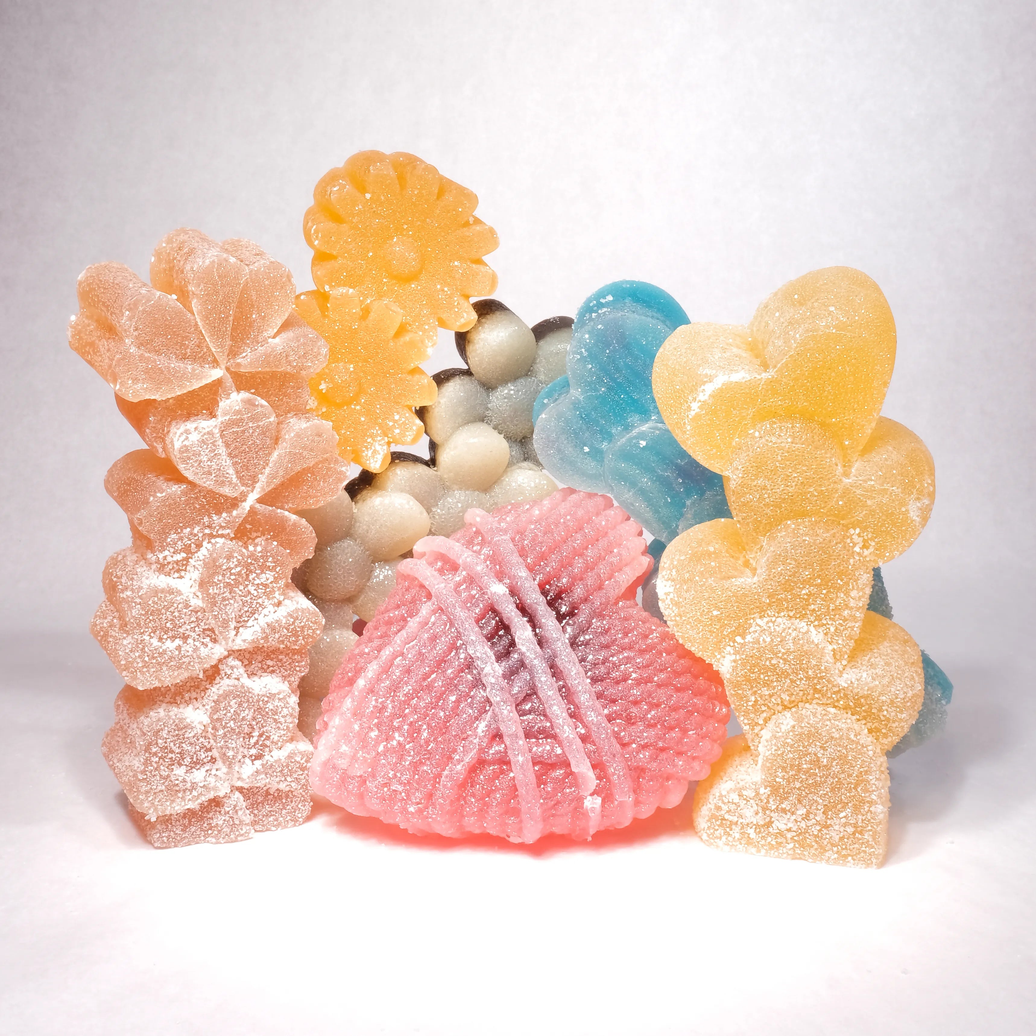 Assorted gummy candies shaped like flowers and leaves on a white background