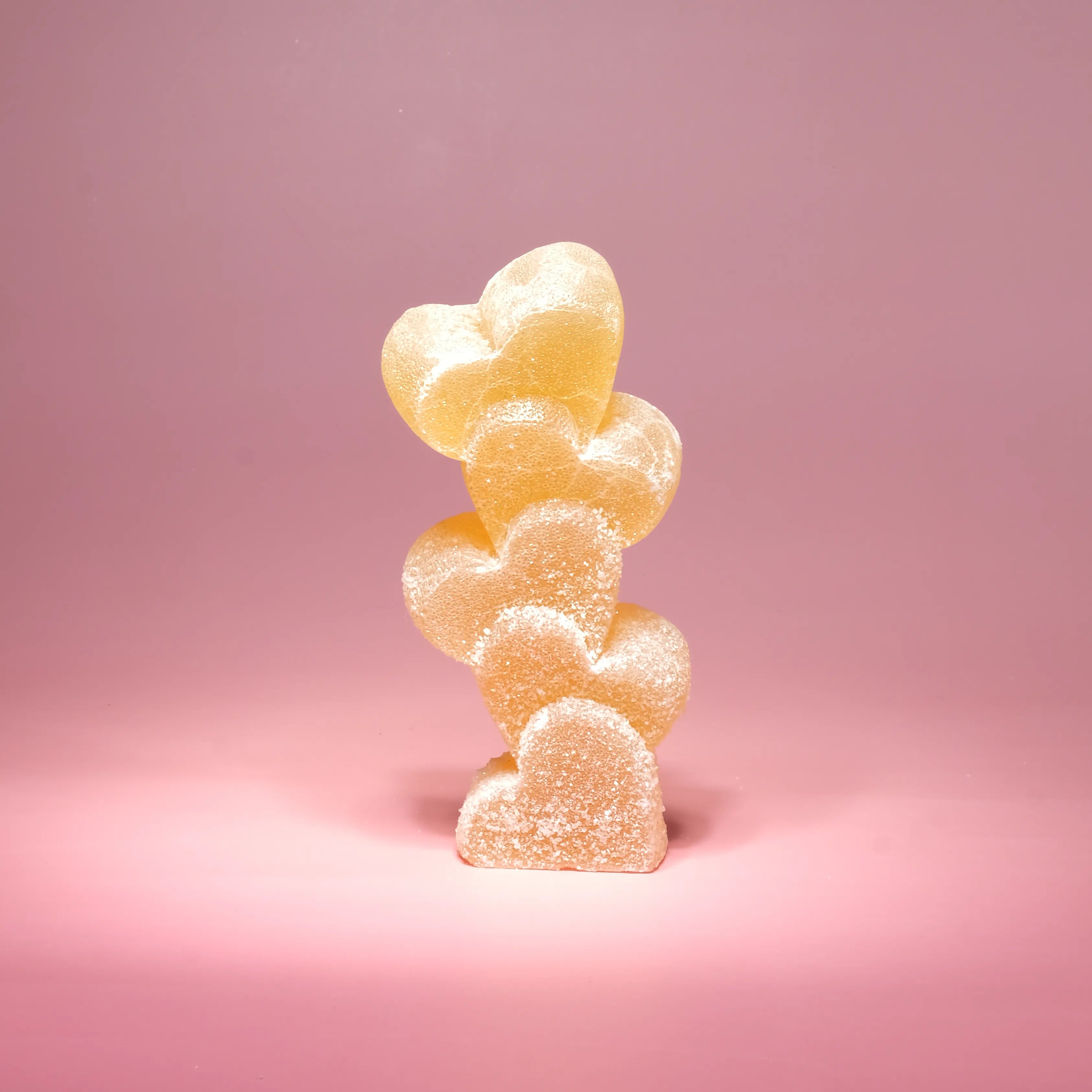 Stack of heart-shaped gummy bears on a pink background