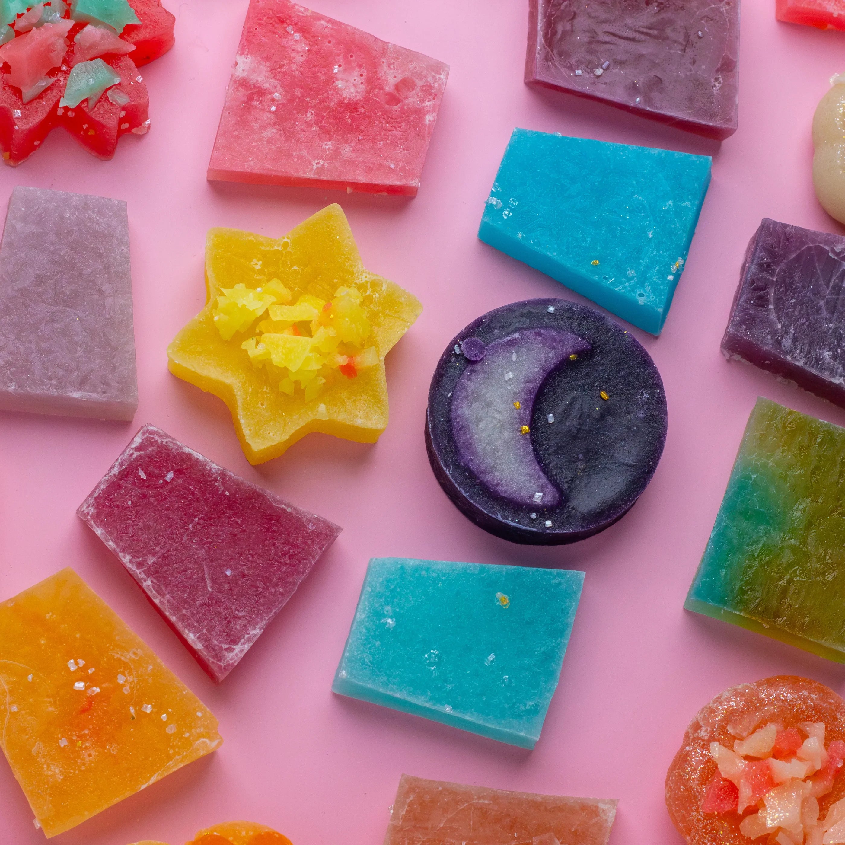 Colorful soap bars with various shapes on a pink background