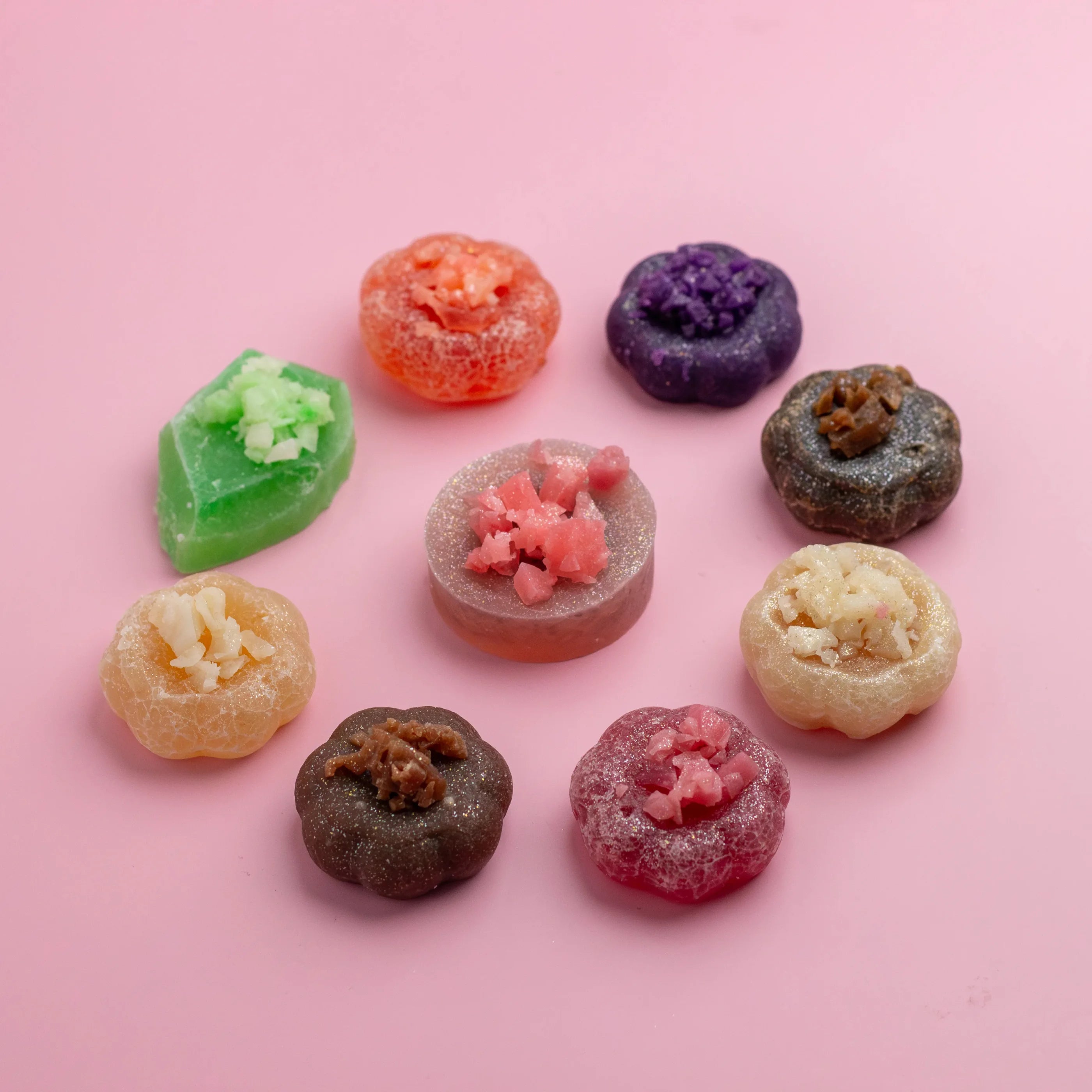 Assorted colorful gummy candies on a pink background