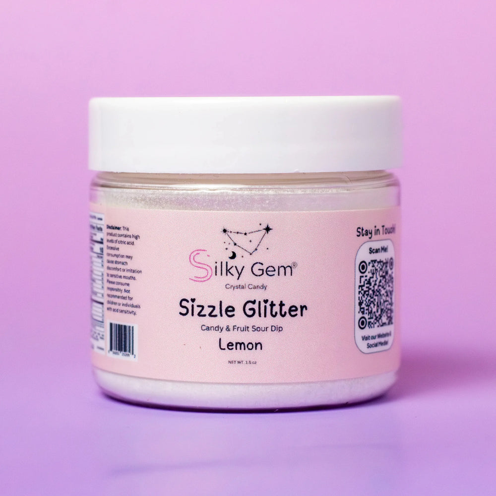 A jar of Silky Gem Sizzle Sour Dip Lemon with a pink label, featuring the brand logo and QR code, displayed against a vibrant pink background.