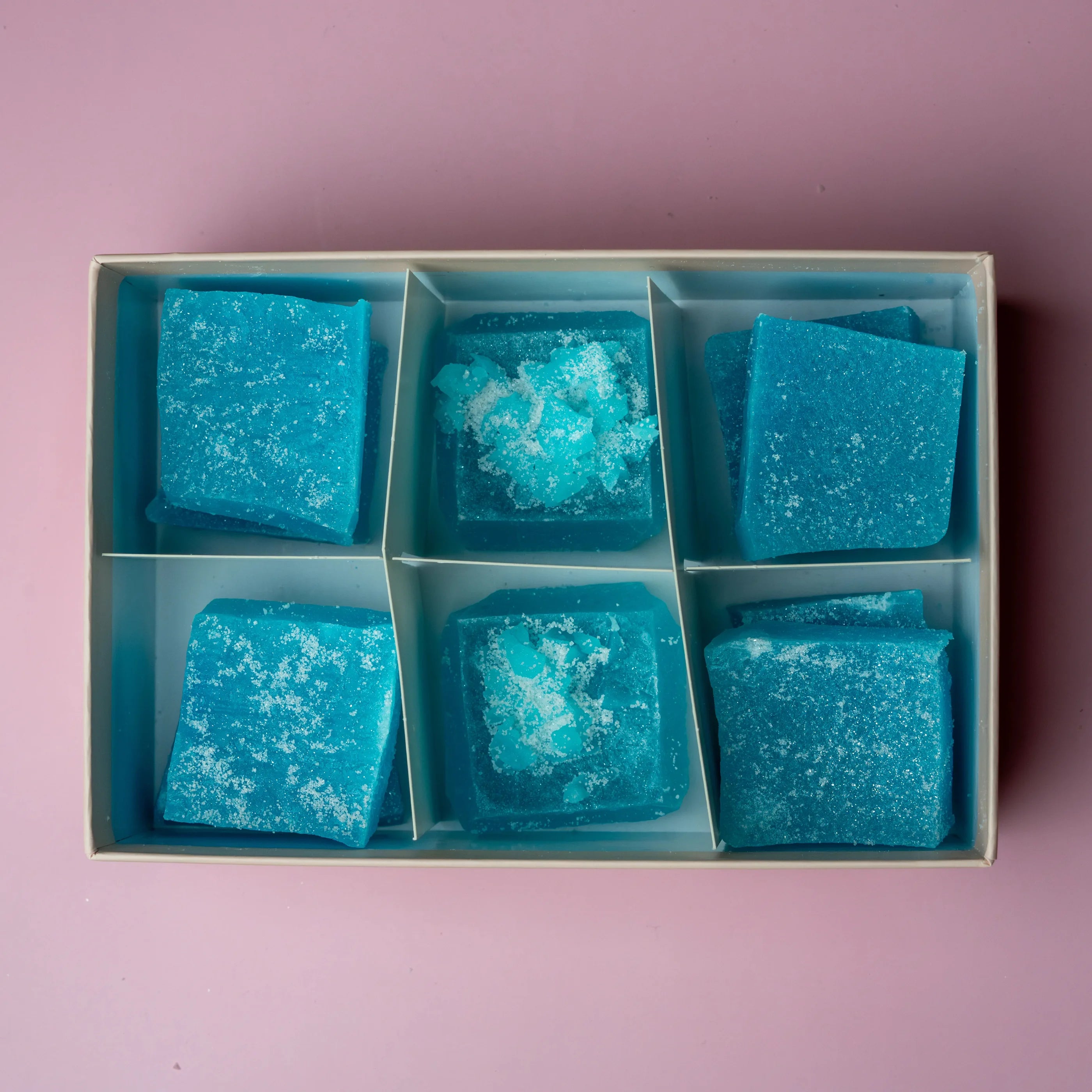 Blue textured cubes in a box on a pink background