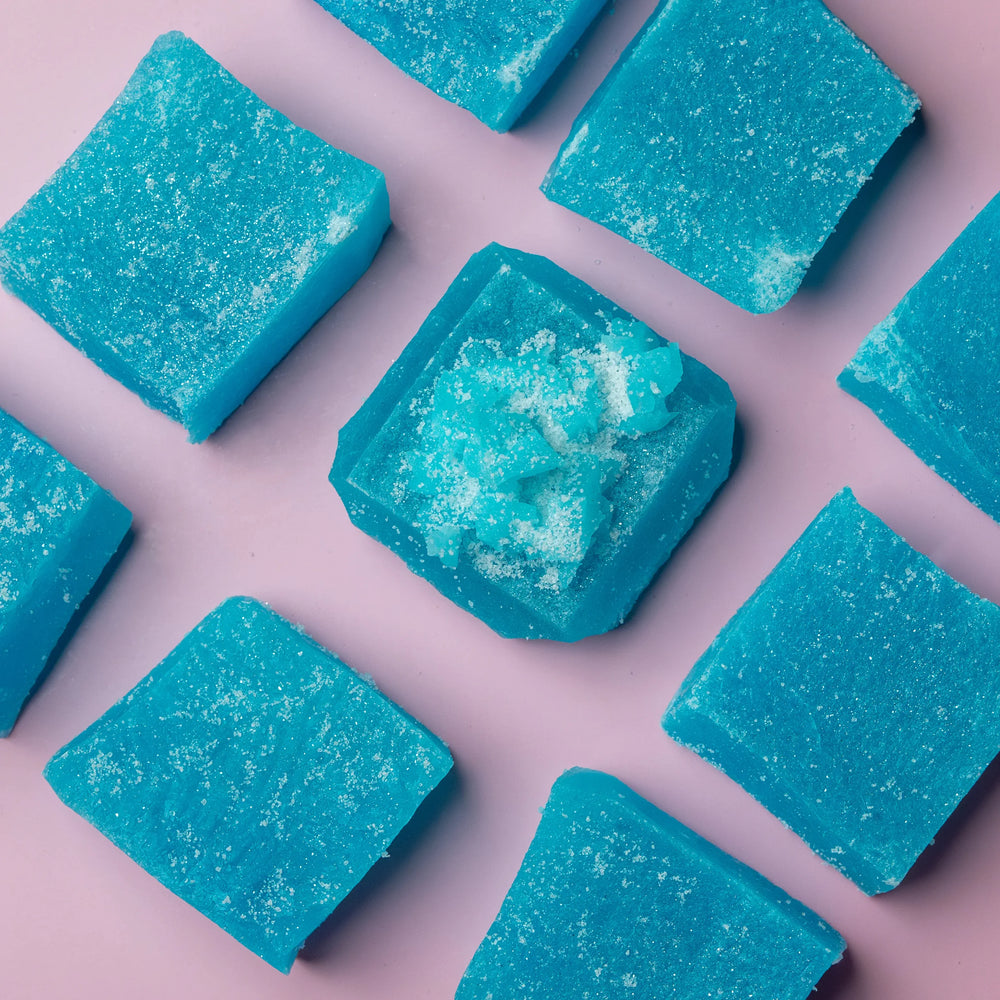 Blue Raspberry Lapis crystal candy pieces arranged on a pink background