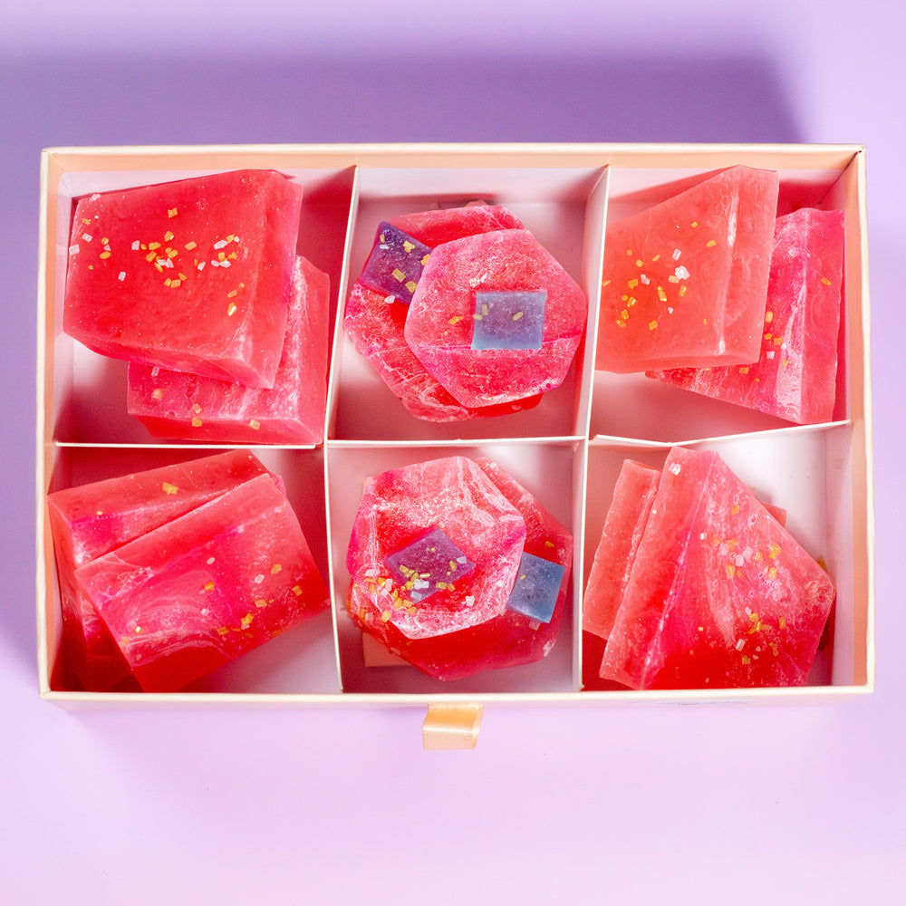 Watermelon Citrus Pink Calcite crystal candy pieces in a gift box on a purple background