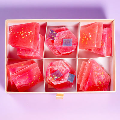Watermelon Citrus Pink Calcite crystal candy pieces in a gift box on a purple background