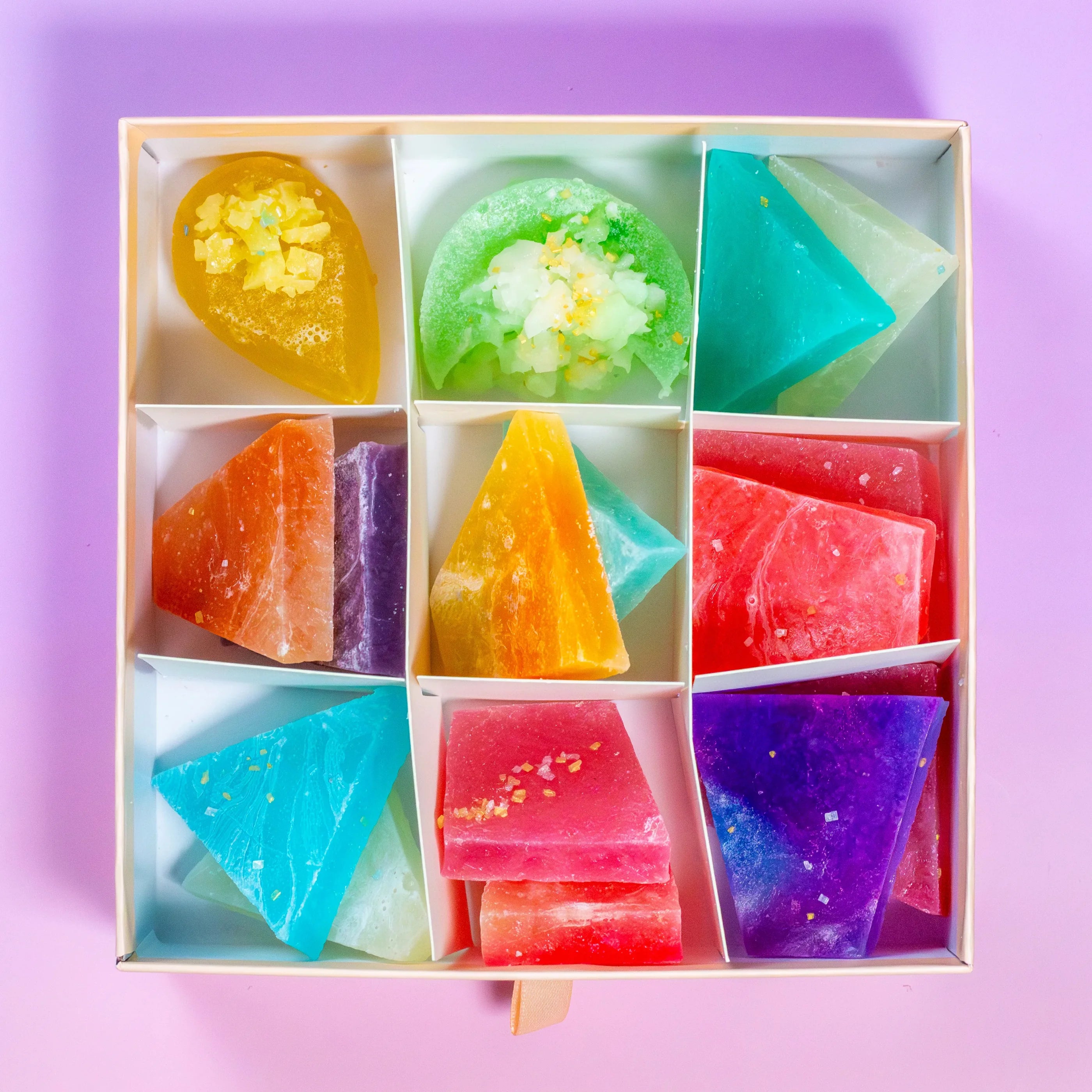 A collection of colorful, geometrically shaped candy sweets displayed in a box, with a variety of flavors.