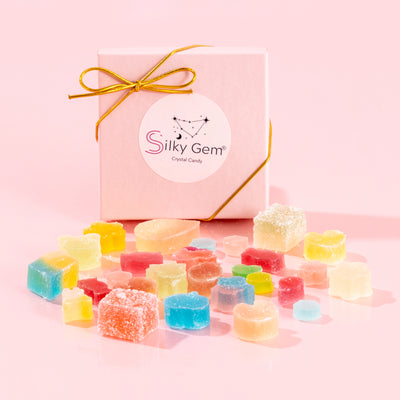 Silky Gem Sweethearts Crystal Box featuring an assortment of handcrafted crystal candy pieces and a gold bow on a pink background.