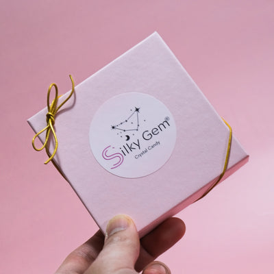 Silky Gem Sweethearts Crystal Box with a gold bow, presented in a premium gift box on a pink background.