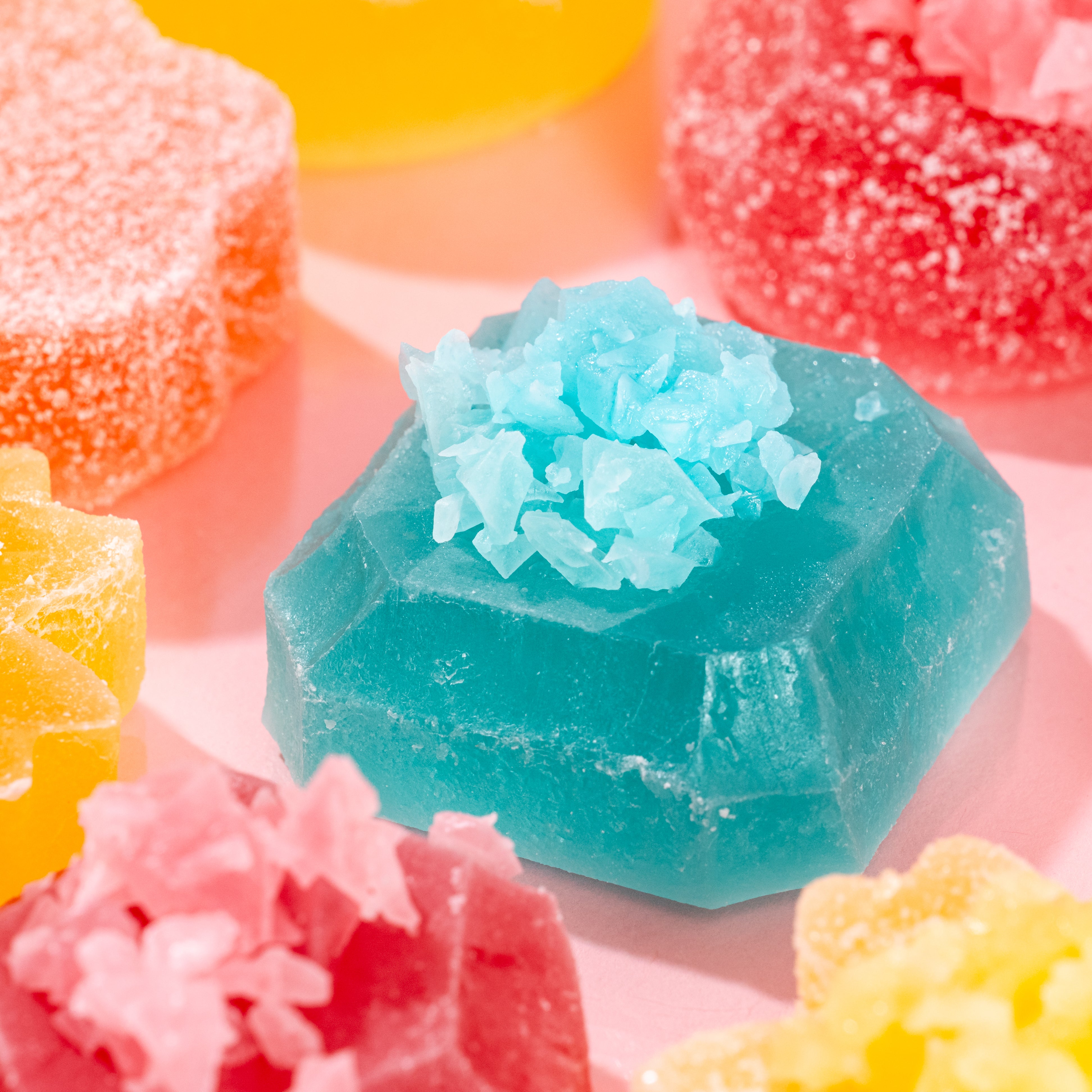 Colorful crystal-like soap bars on a soft pink background