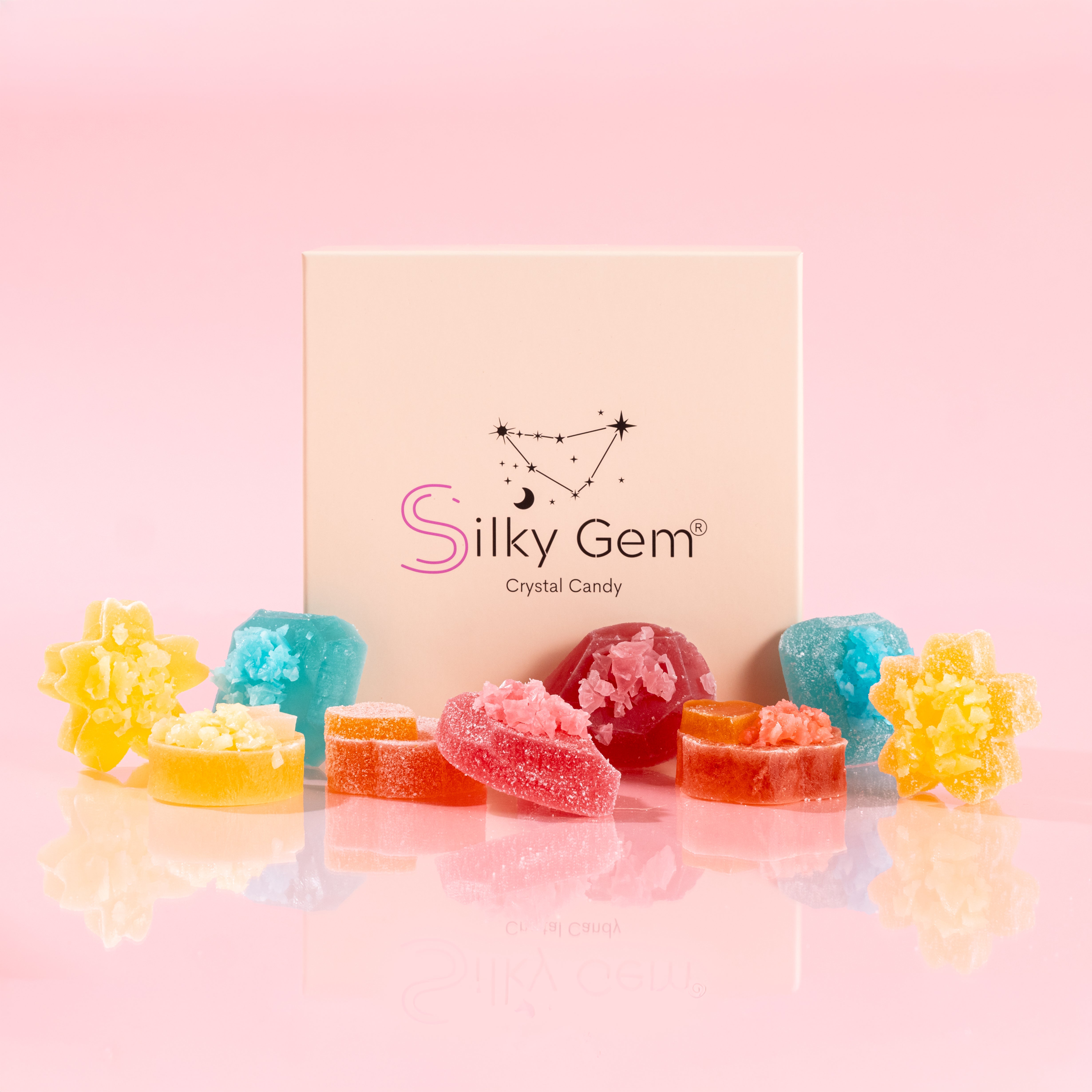 Colorful crystal candies in front of a 'Silky Gem' branded box on a pink background