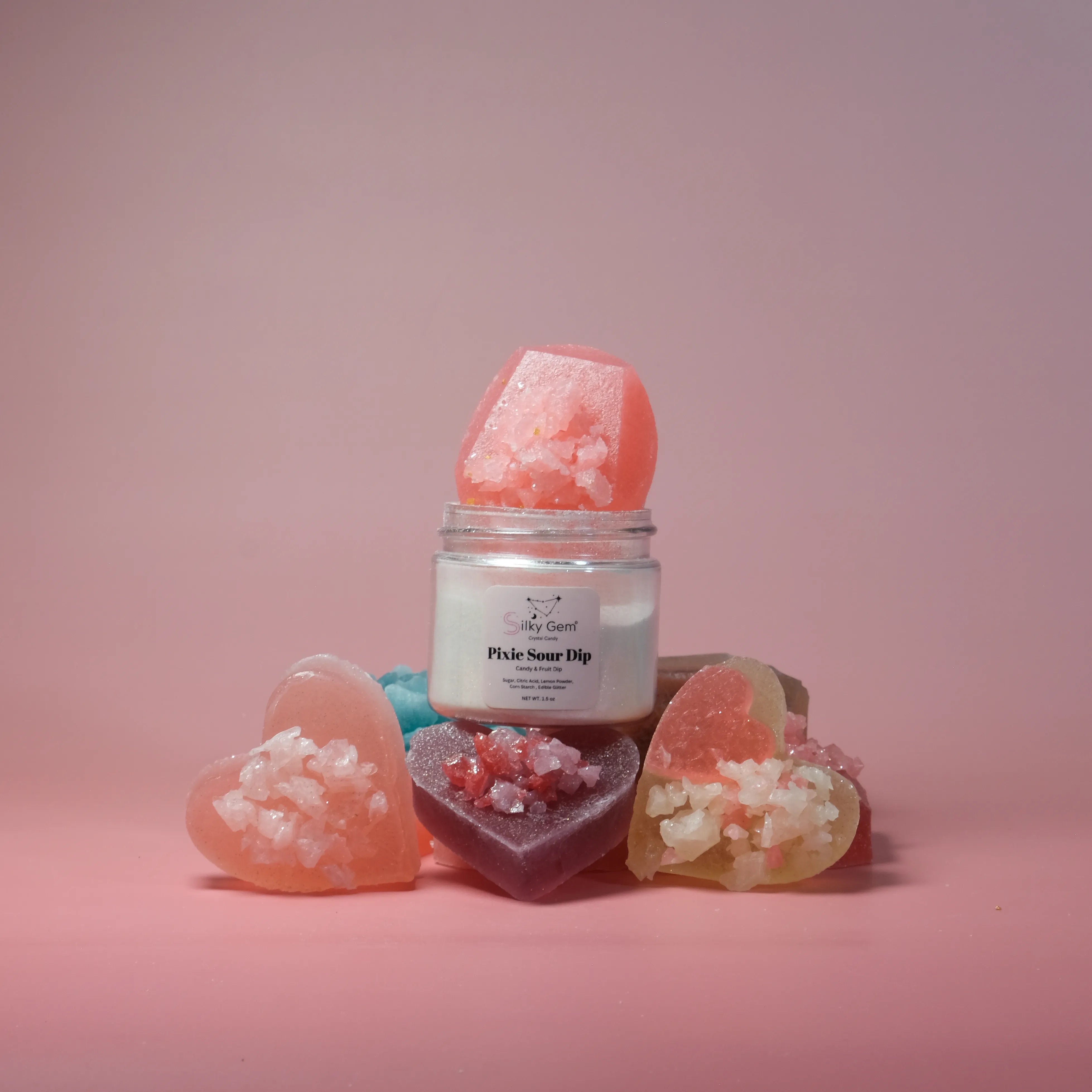 Jar of 'Pixie Sour Dip' with heart-shaped gummies on a pink background