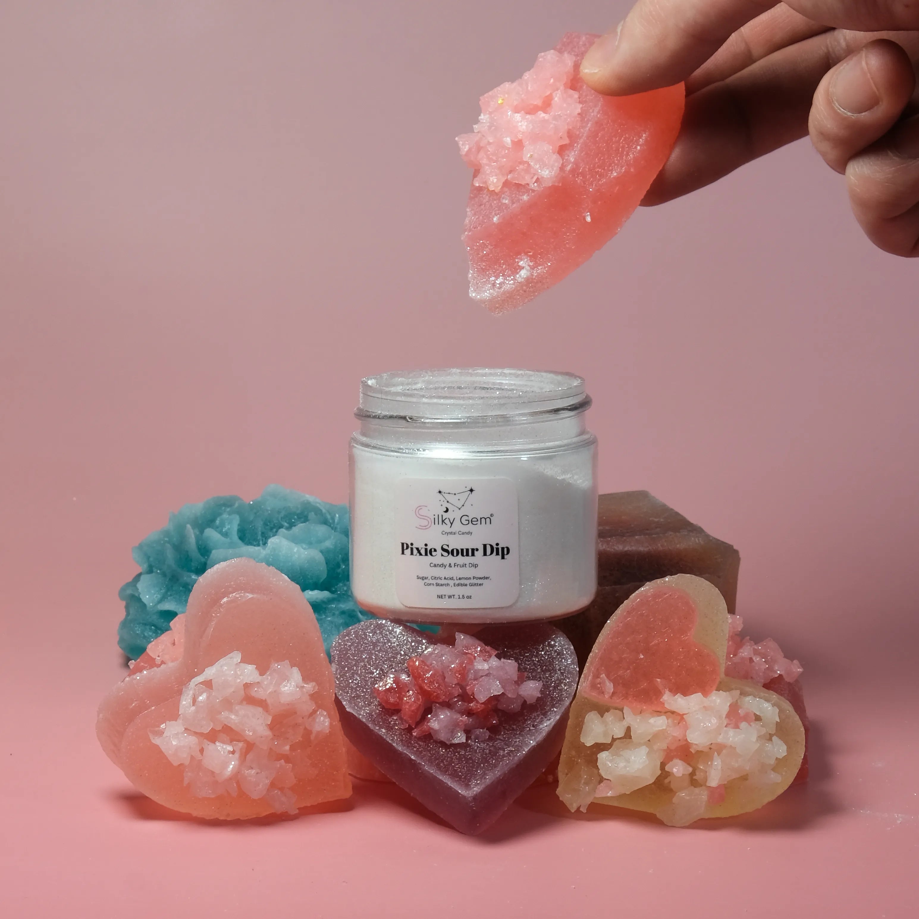 Jar of 'Pixie Sour Dip' with heart-shaped gummies on a pink background